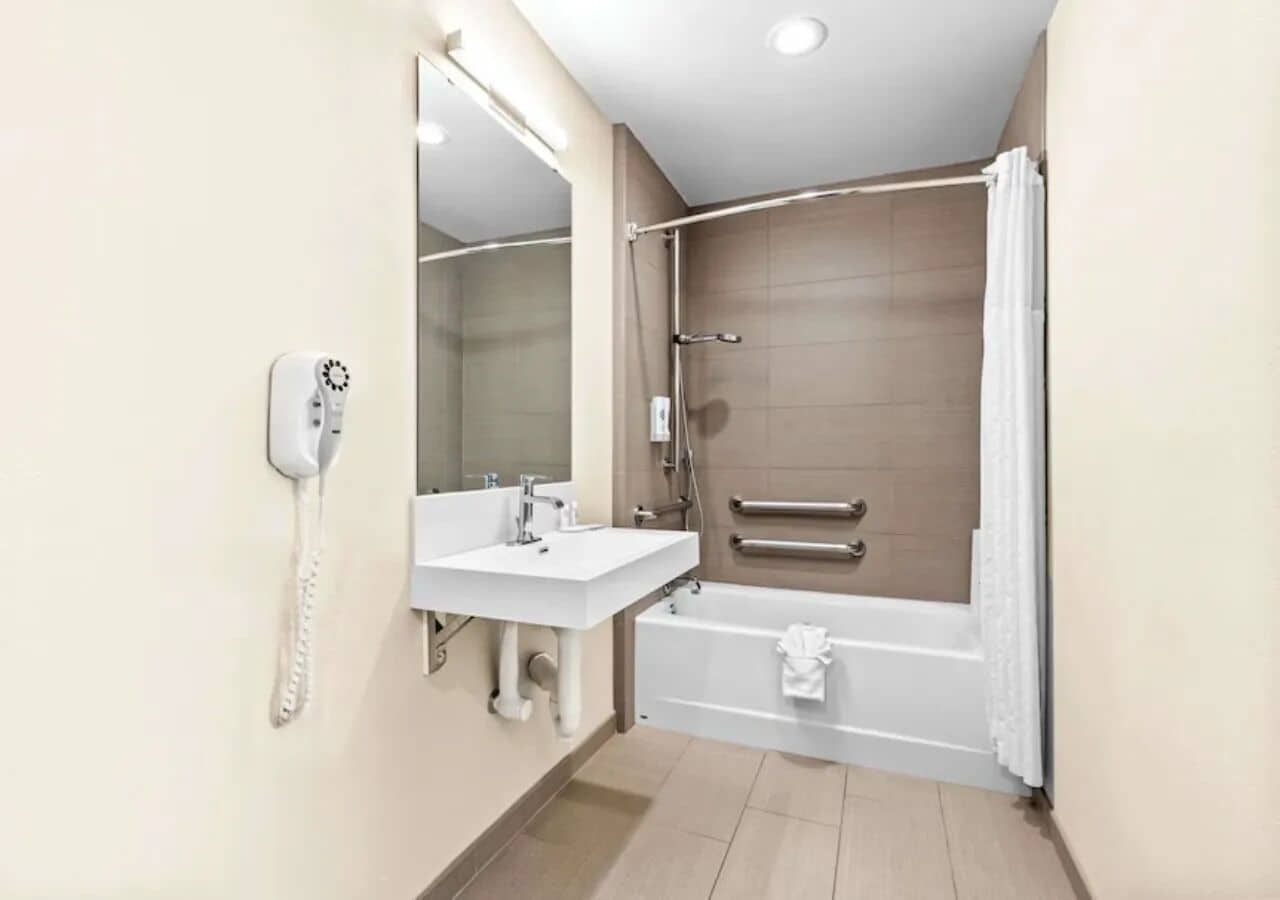 A modern bathroom with a white sink, mirror, and bathtub.