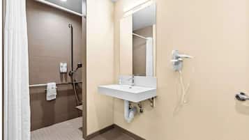 Un baño con ducha, lavamanos, espejo y teléfono.