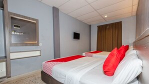 A hotel room with two beds, a television, a wooden headboard, and a window with blinds. - Hotel Q Banda Kaba (Malacca City)