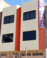 Un edificio de varios pisos con una fachada destacada en rojo y blanco, que cuenta con ventanas grandes y un letrero de neón que anuncia un hotel.