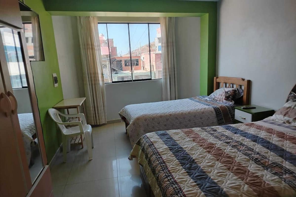 A bedroom with two beds, a desk, and a chair.