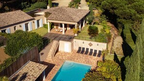 Una propiedad residencial con piscina, un porche cubierto y jardín.