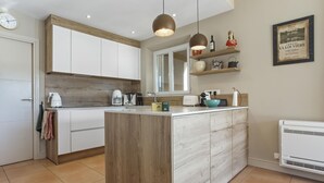 Una cocina moderna con una isla central, armarios de madera e iluminación colgante.
