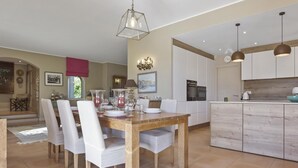 Una cocina moderna con armarios blancos, una isla de madera e iluminación colgante.