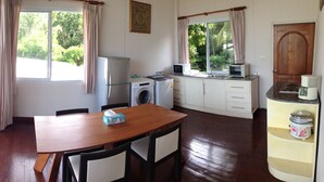A compact kitchen with a dining area, a washing machine, and a coffee maker. - Room-nakara Samui-2 Bedrooms Ocean View (Koh Samui)