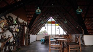 Un intérieur caractérisé par un plafond haut et incliné, des meubles en bois et une grande fenêtre ornée d’un vitrail aux couleurs vives.