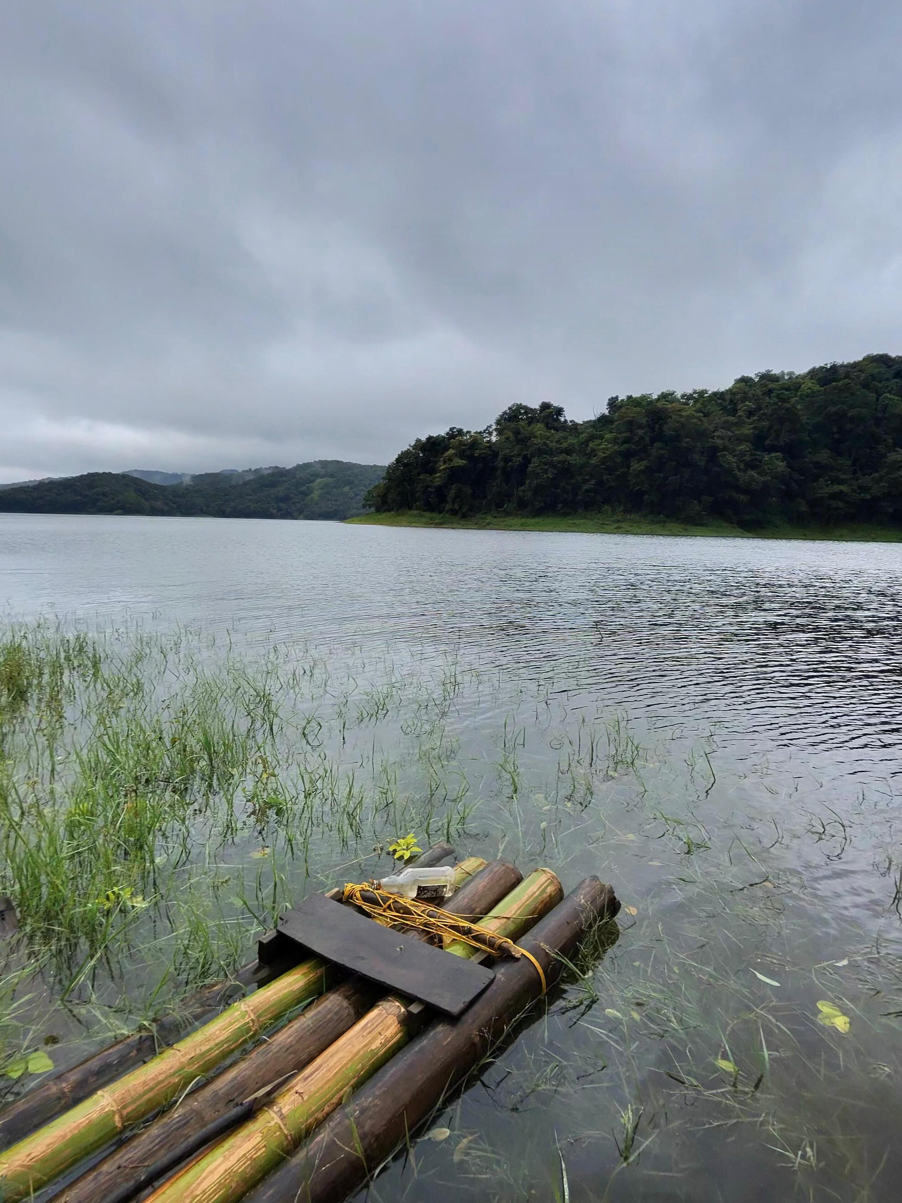 A calm lake with a floating dock made of bamboo and wood.