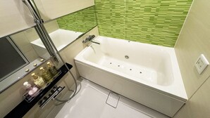 A modern bathroom with a white bathtub, a vanity with a mirror, and a green tiled wall. - Hotel La'i Laurel (Tokyo)