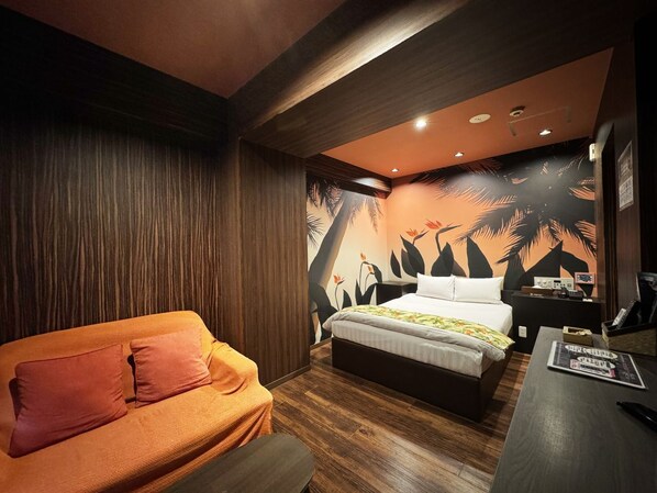 A bedroom with a bed, a sofa, a desk, and a wall with a tropical mural.