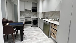 Ett modernt kök med vita skåp, en inbyggd ugn, en tvättmaskin och en diskmaskin.