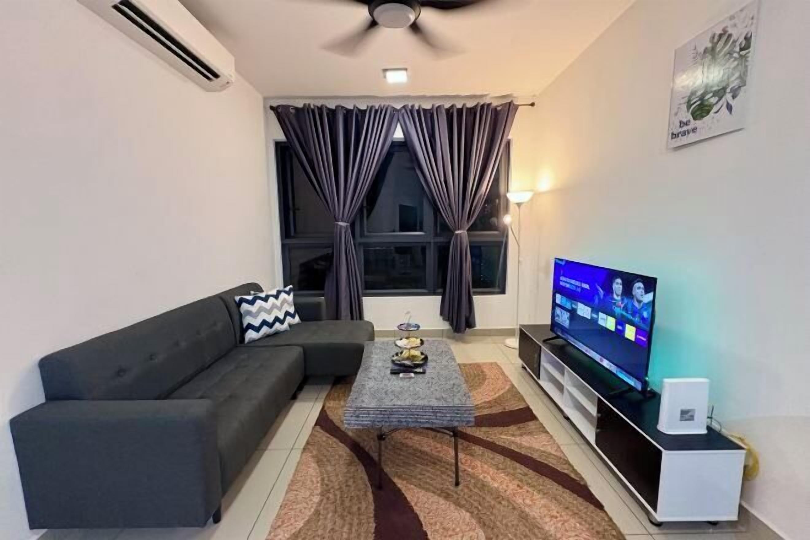 A modern living room with a sofa, a coffee table, a TV, and a ceiling fan.