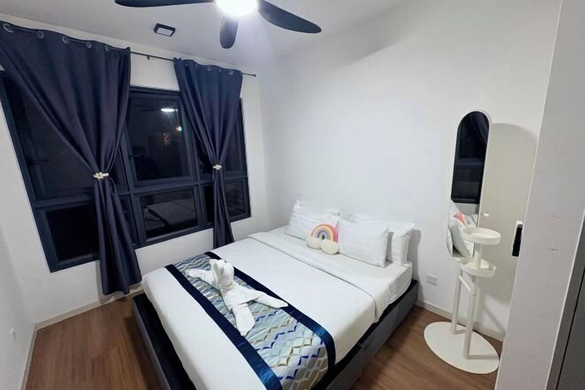 Una habitación de hotel con cama, cortinas, ventilador de techo, mesita de noche y espejo.