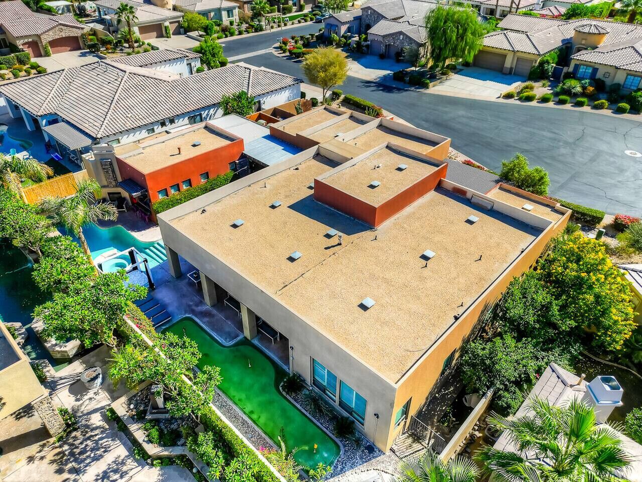 A modern building with a flat roof, a swimming pool, and a well-maintained garden.