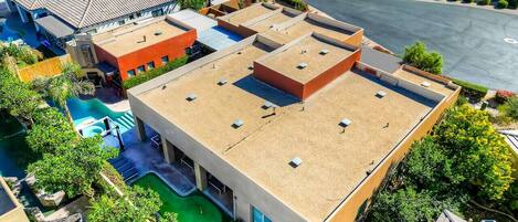 A modern building with a flat roof, a swimming pool, and a well-maintained garden.