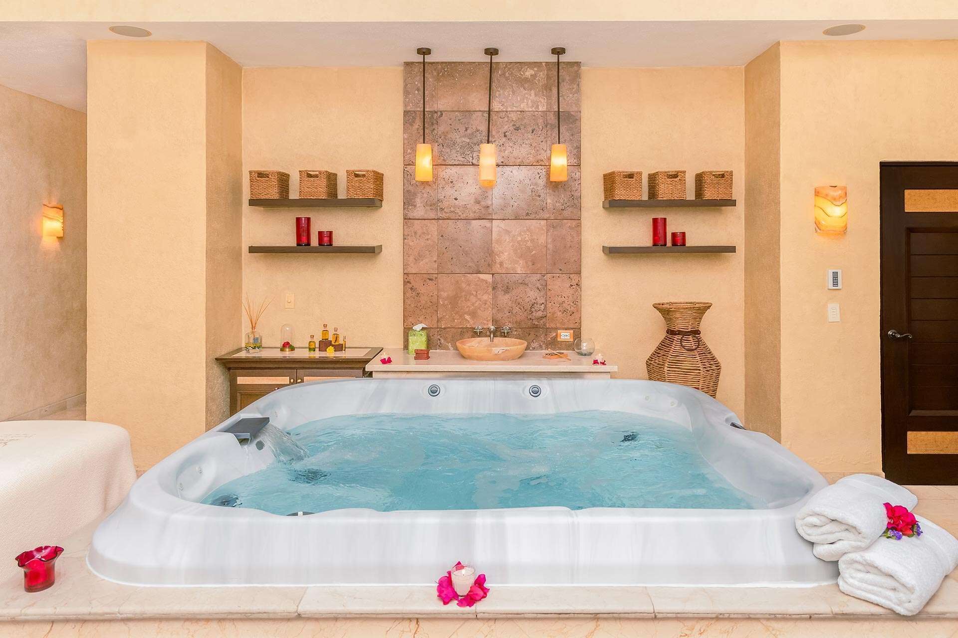 Et spa-rum med jacuzzi, hylder med stearinlys og en stenvæg.