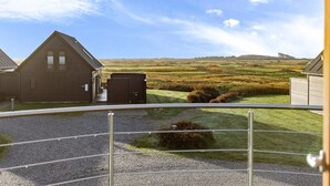 Een landelijke omgeving met twee houten gebouwen, een grindpad en een grasveld.