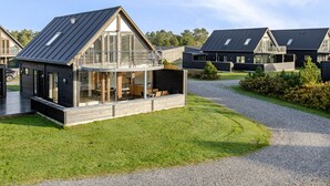 Een modern vakantiehuis met een groot balkon, een overdekt terras en een verzorgd gazon.