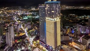 Un hôtel de grande hauteur, avec de nombreux étages, une entrée imposante et une vue sur le paysage urbain environnant la nuit.