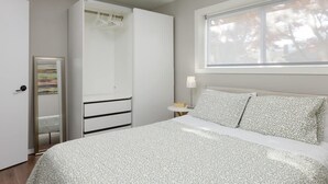 A bedroom with a bed, a wardrobe, a bedside table, and a window. - Coho Trailside Comforts (Squamish)
