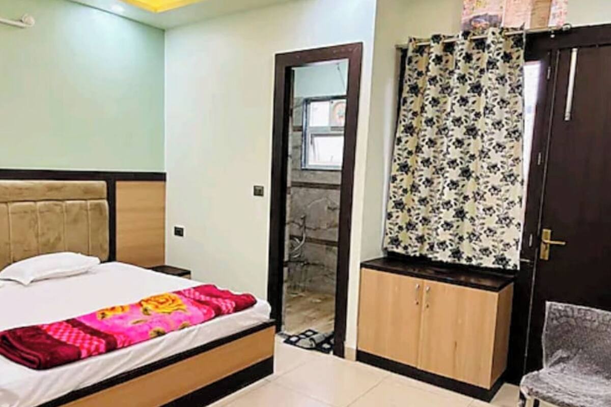 A bedroom with a bed, a wardrobe, a chair, and a door leading to another room.