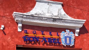 La entrada de un hotel con fachada roja y un letrero que dice "HOTEL DONABEL".