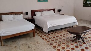 Una habitación con dos camas de madera, una mesita redonda y baldosas de suelo estampadas.