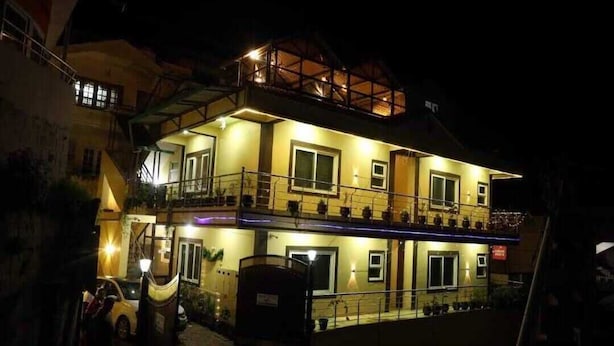 A two-story building with balconies, a car parked in front, and a gated entrance. - Essar Cottage (Ootacamund)