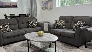 A modern living room with two grey sofas, a round coffee table, and a patterned rug. - Fully Furnished 3BR/2BA Condo with Balcony. Close to Airport, Shopping & Dinning (McAllen)