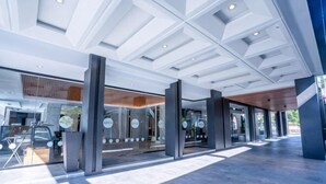 L’entrée moderne de l’hôtel se distingue par sa façade en verre, un espace extérieur couvert aménagé en salon et un hall d’entrée spacieux.