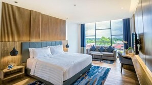Une chambre d’hôtel moderne, dotée d’un grand lit, d’un canapé, d’une télévision et offrant une vue sur l’extérieur.