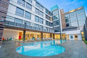 Ein modernes Hotel mit Poolbereich, mehreren Etagen und einer Fassade aus Glas und Backstein.