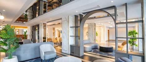A spacious lobby with a high ceiling, seating areas, and a large window.