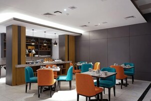 Un comedor moderno con mesas y sillas, una barra y una cocina al fondo.