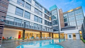 Un hôtel moderne doté d’une piscine, d’un espace extérieur aménagé et d’une façade bien éclairée.