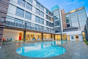 Un hotel moderno con piscina, zona de estar al aire libre y fachada bien iluminada.