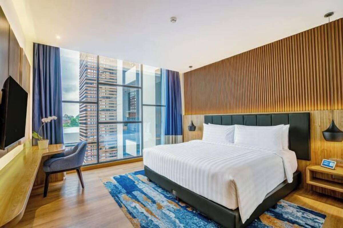 Habitació d'hotel moderna amb un llit gran, una taula de treball i una televisió.
