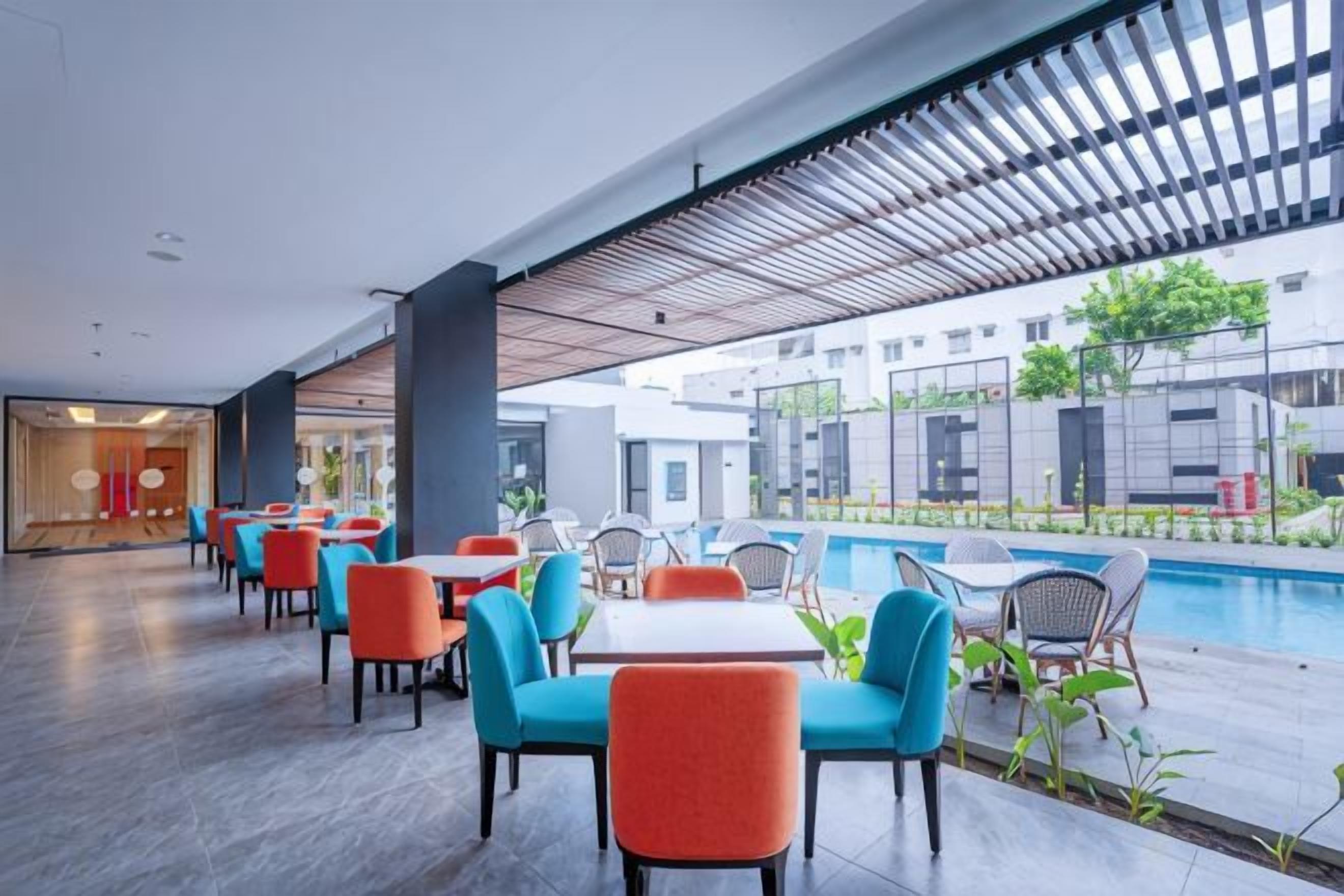 A modern outdoor seating area with tables and chairs, a pool, and a view of the surrounding buildings.