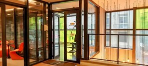Um interior moderno com portas de vidro que dão para uma área de estar com cadeiras vermelhas.