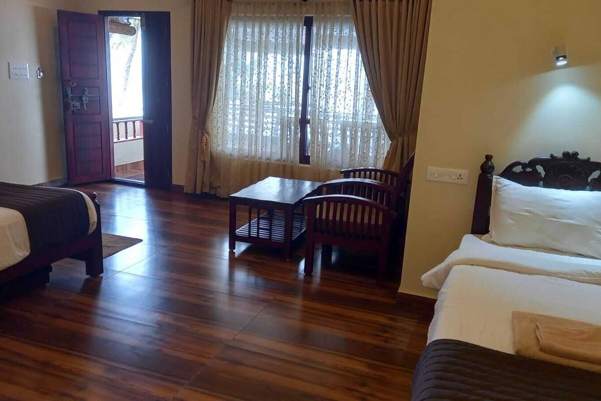 Habitació d'hotel amb dos llits, un sòl de fusta, una taula i una cadira.