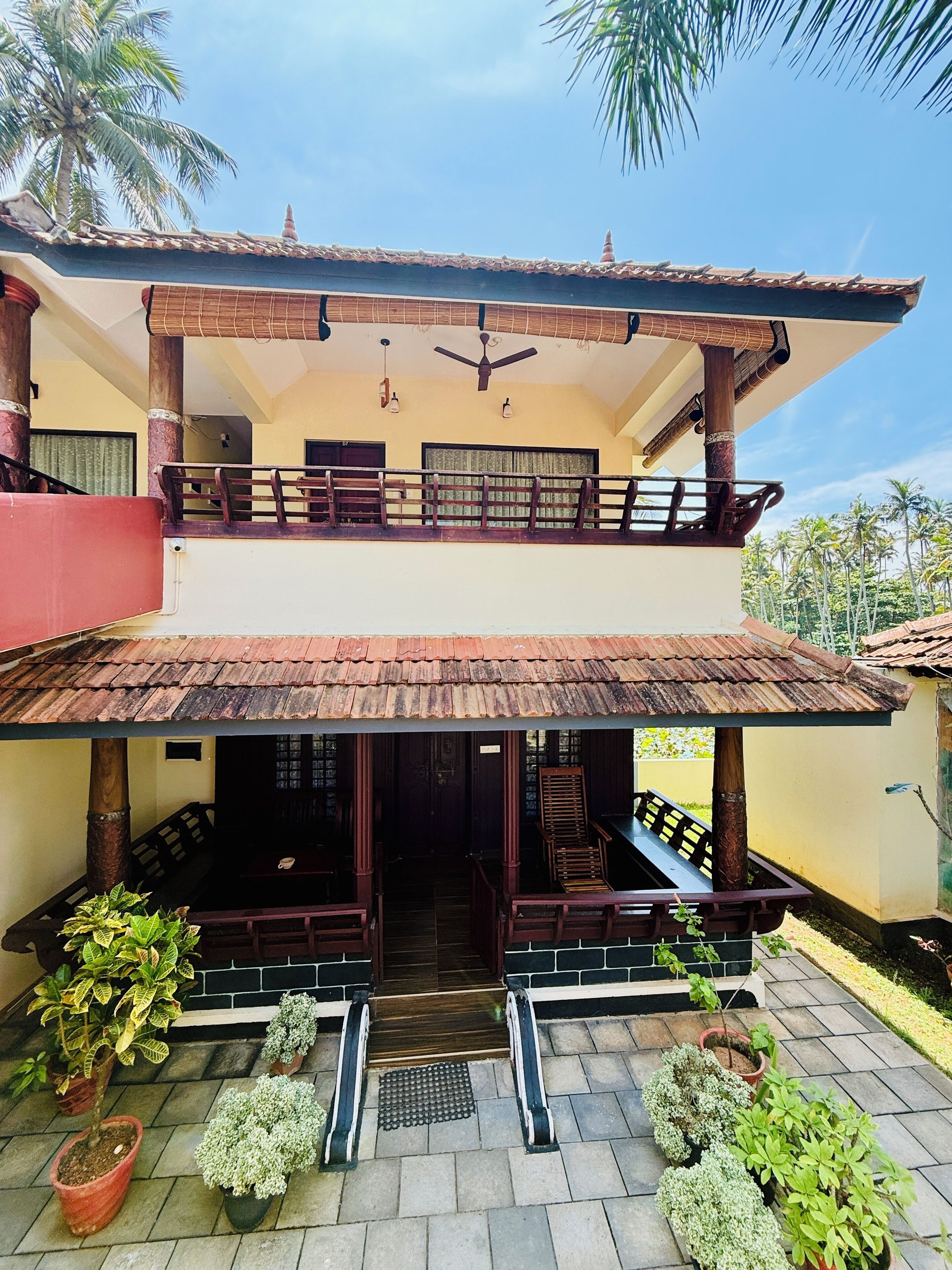 A two-story building with a balcony, a ceiling fan, and a tiled roof.