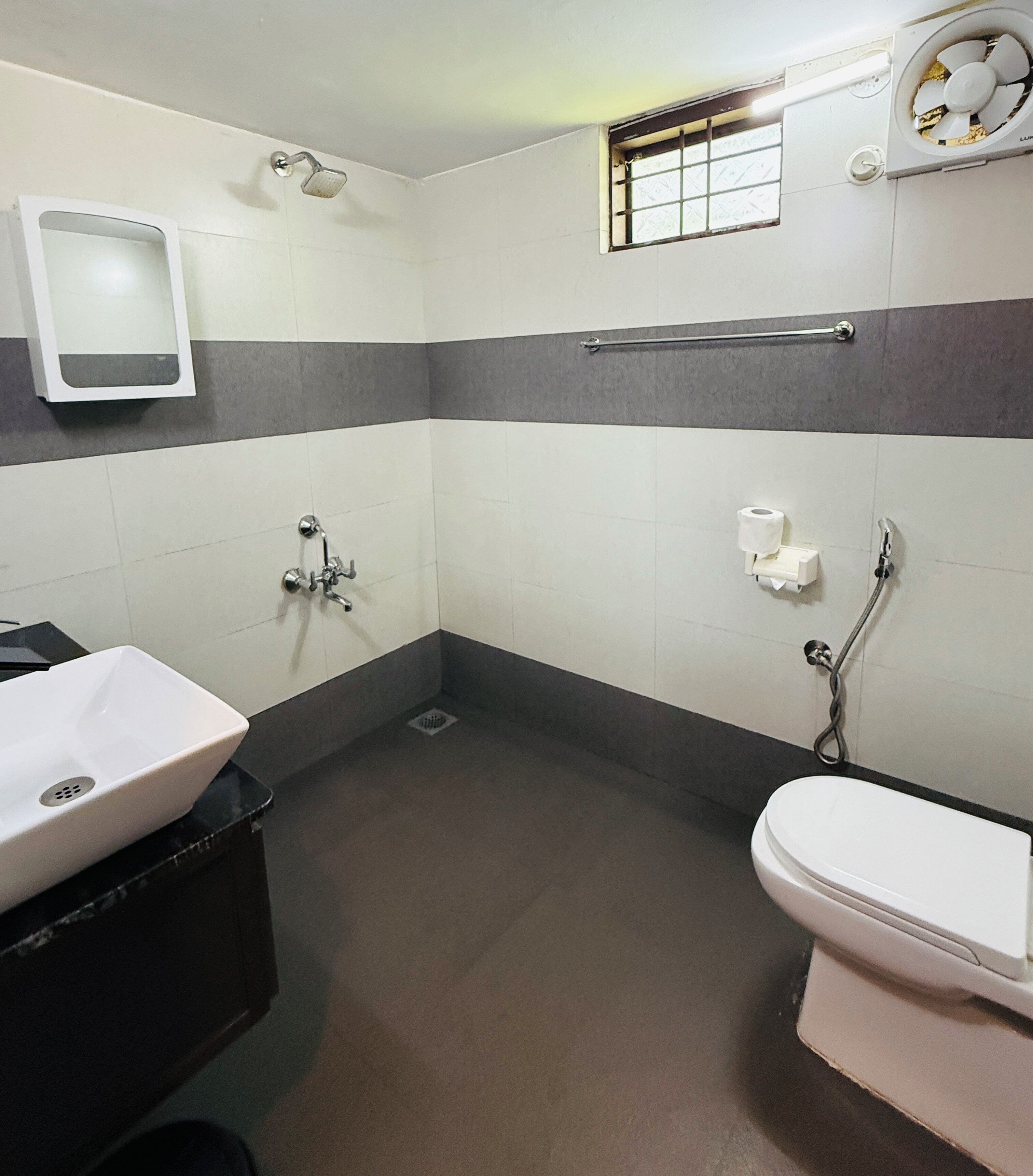 A bathroom with a white sink, a toilet, a shower, and a hand dryer.