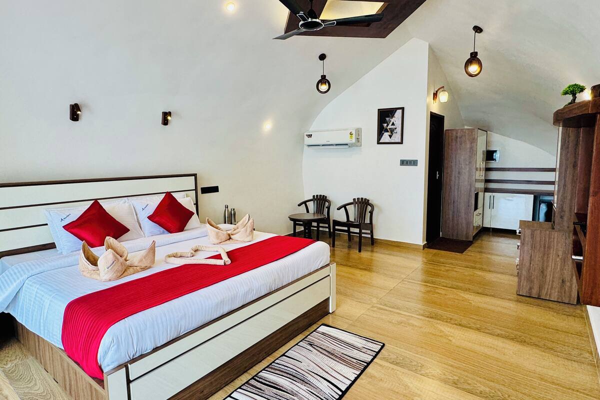 Habitació d'hotel moderna amb un llit gran, una taula petita i una cuineta.