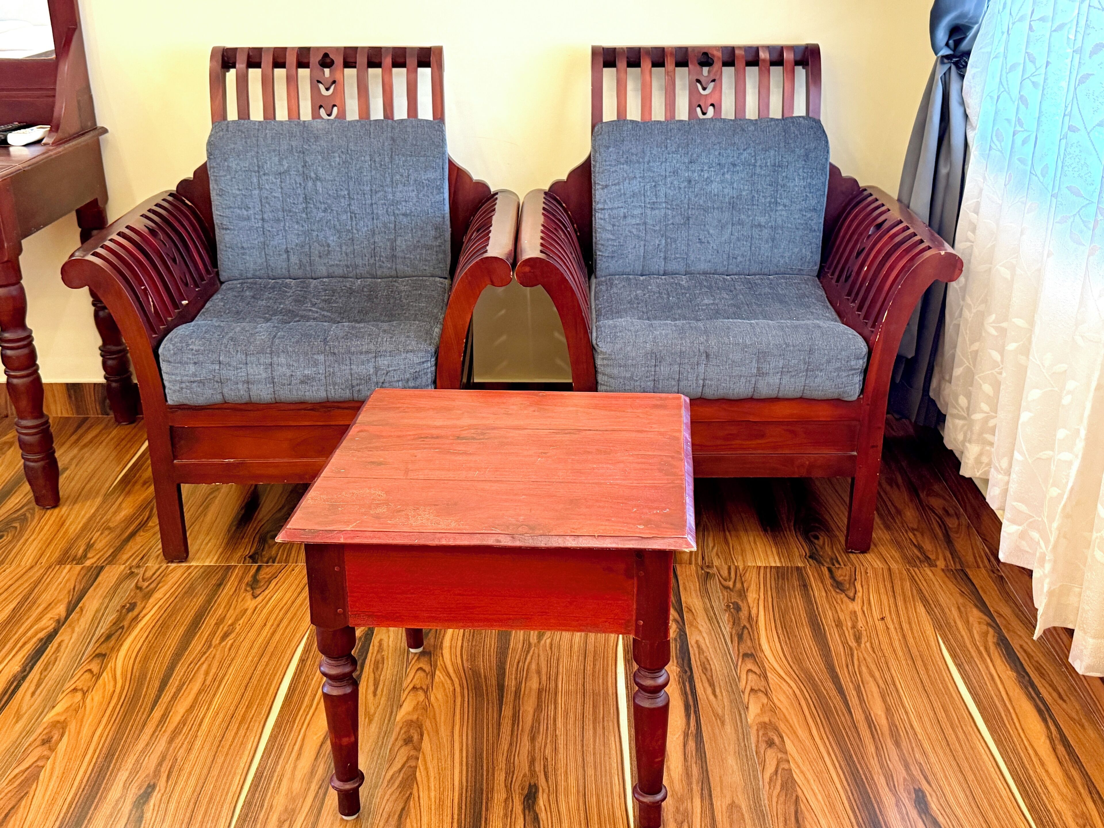 A wooden sofa set with grey cushions and a matching wooden table in a room with wooden flooring.