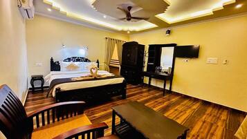 A hotel room with a bed, a desk, a chair, a TV, and a ceiling fan.
