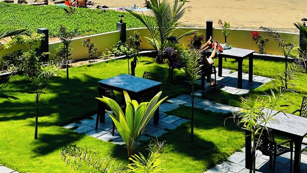 A beachfront patio with outdoor seating and a view of the ocean. - Maadathil cottages & Beach resort (Varkala)