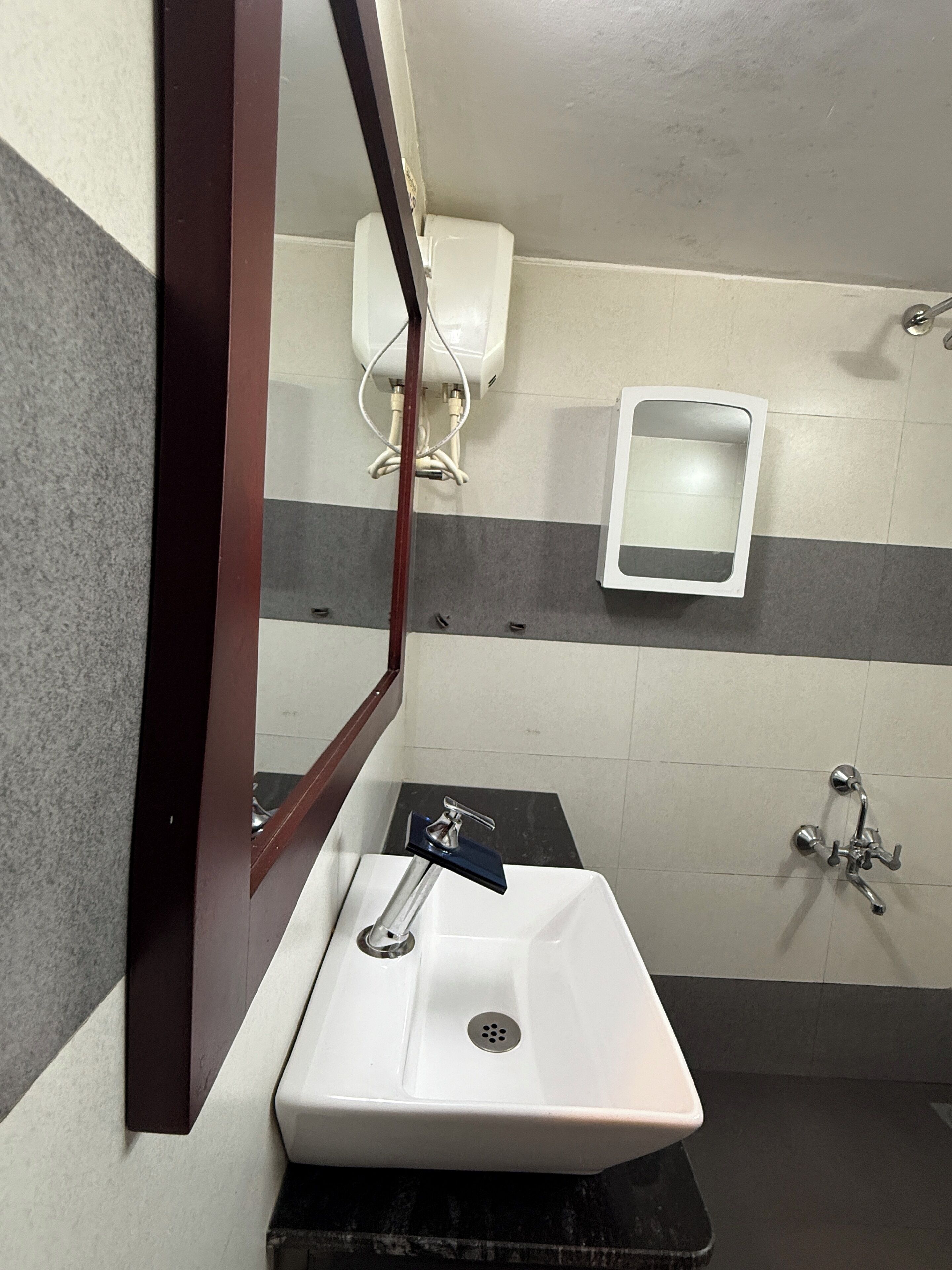 Een badkamer met een witte wastafel, een spiegel, een toilet en een douche.
