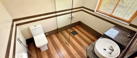 A bathroom with a toilet, shower, and sink.