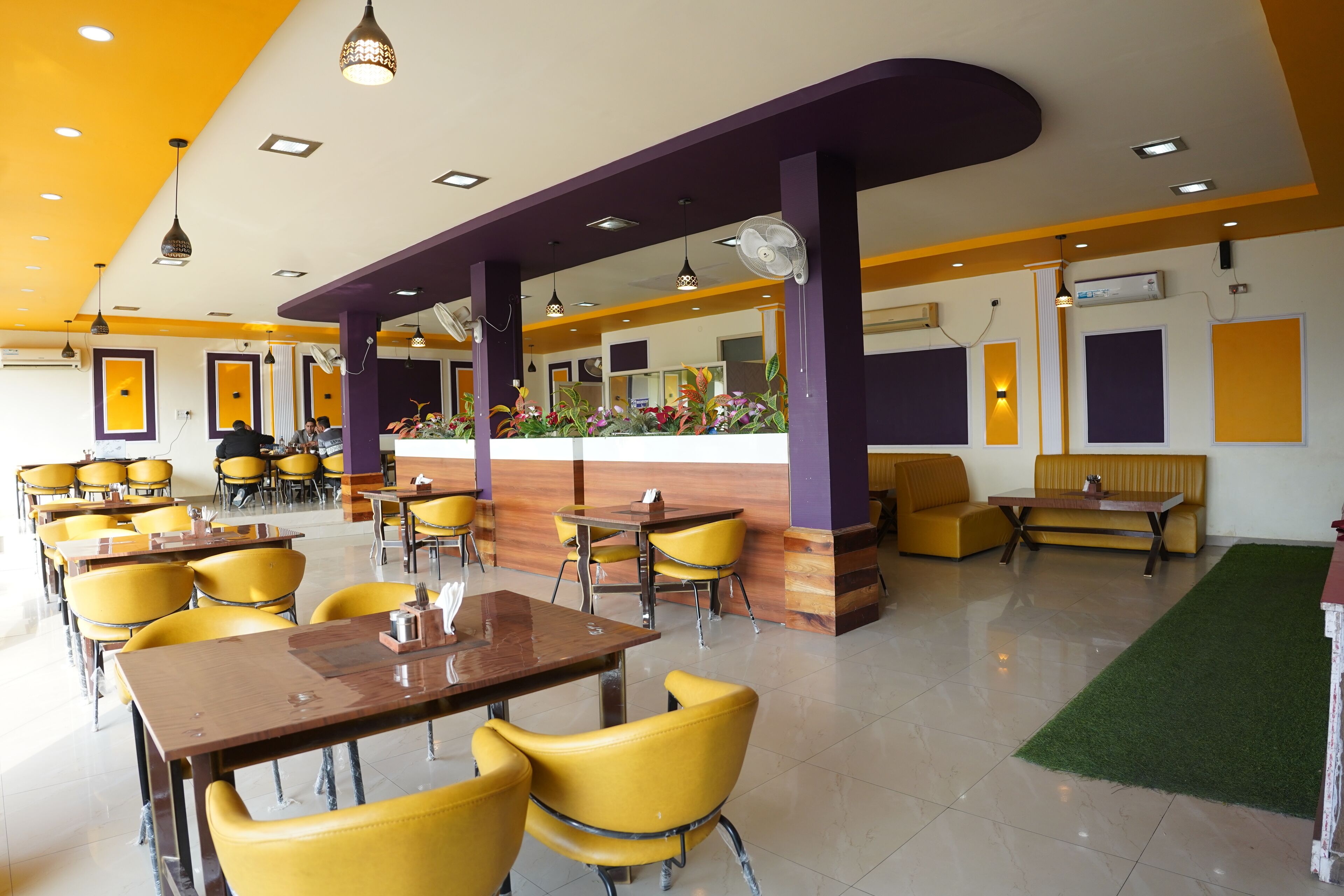 A restaurant with yellow chairs, a counter, and purple accents.