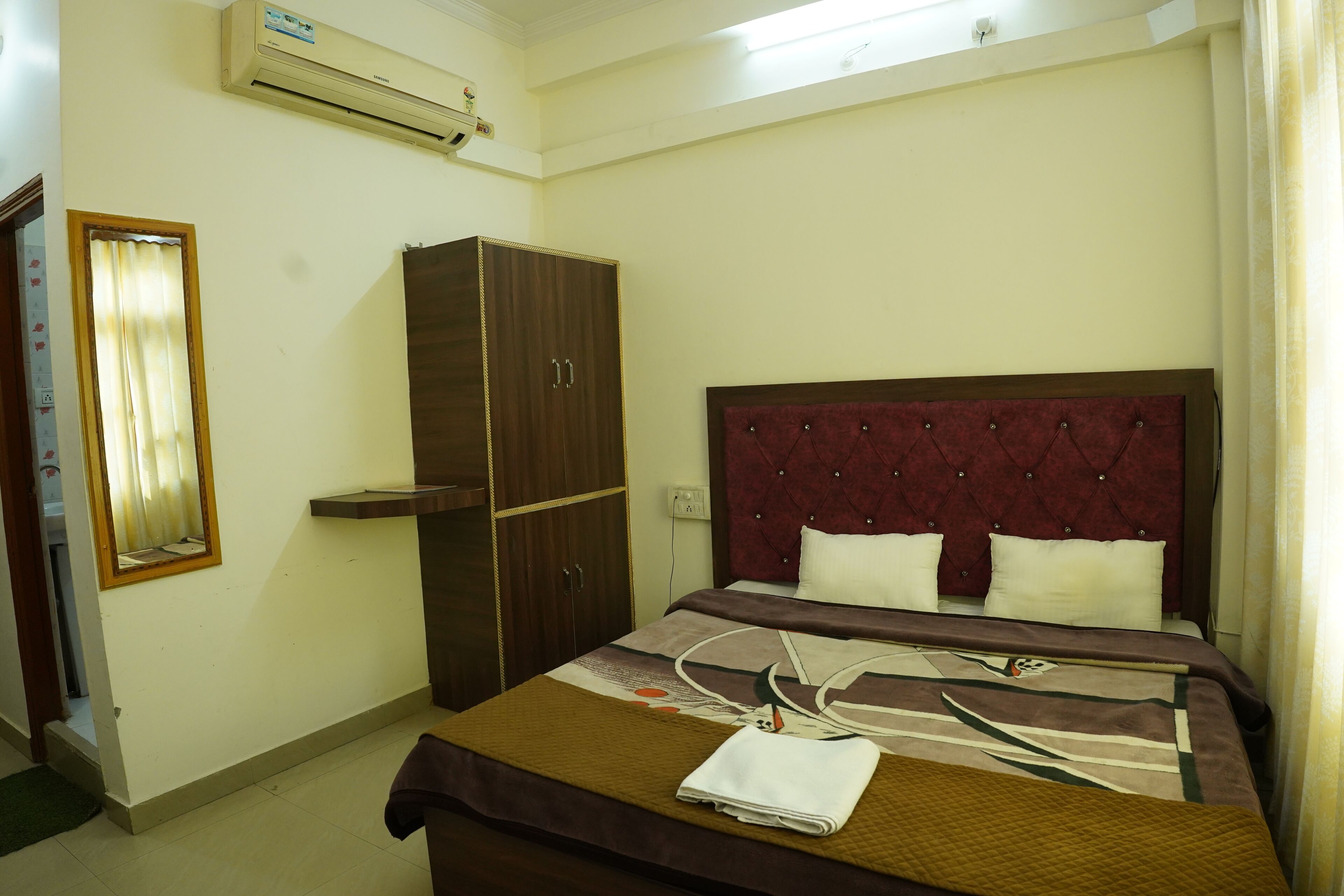 Una habitación de hotel con cama, armario, espejo y aire acondicionado.