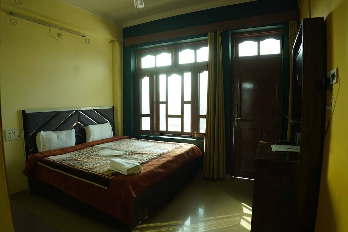 A bedroom with a bed, a window with curtains, and a door.